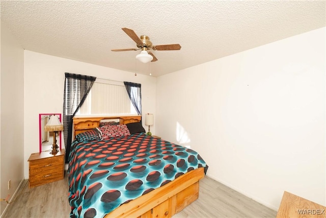 bedroom featuring light wood finished floors, ceiling fan, baseboards, and a textured ceiling