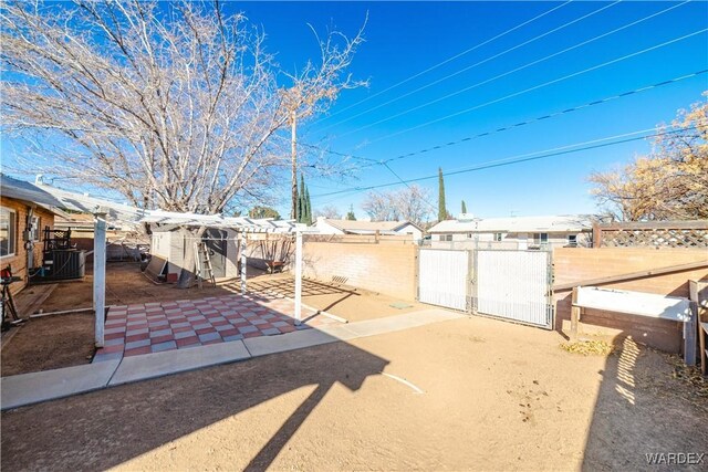 view of yard featuring central AC, a patio area, a fenced backyard, and a gate