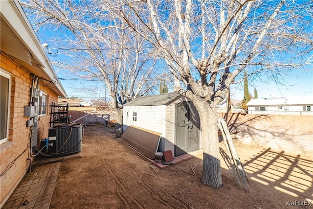 view of yard featuring a storage shed, an outdoor structure, a fenced backyard, and central air condition unit