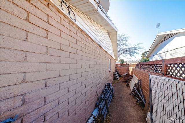 view of side of property featuring fence and brick siding