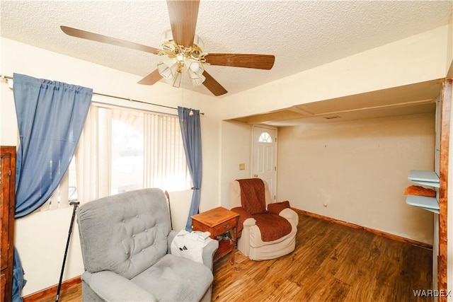 sitting room with a textured ceiling, baseboards, and wood finished floors