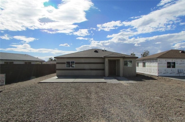 rear view of property featuring stucco siding, a patio, and fence