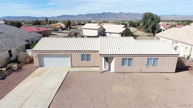 view of front of home featuring a tile roof, stucco siding, a mountain view, a residential view, and driveway