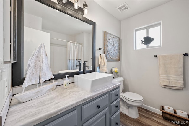 bathroom featuring visible vents, toilet, vanity, wood finished floors, and baseboards