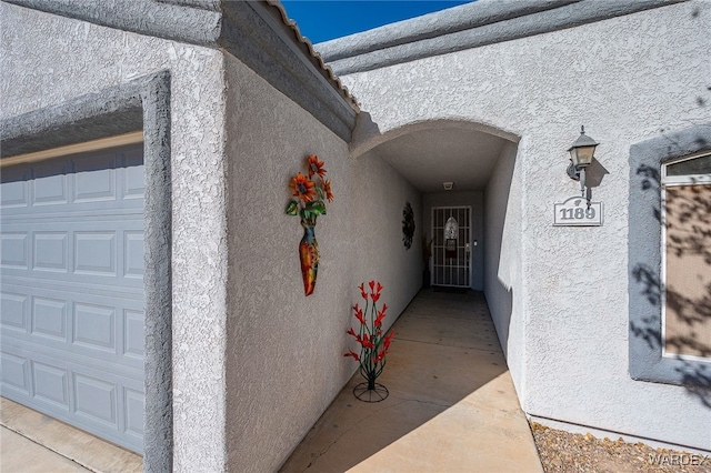 view of exterior entry with a garage and stucco siding