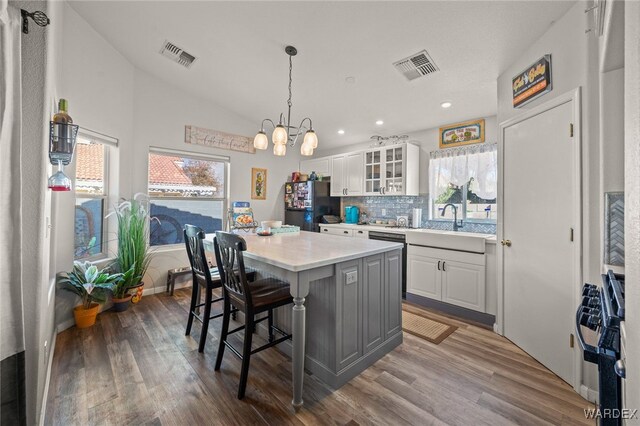 kitchen featuring light countertops, freestanding refrigerator, glass insert cabinets, and white cabinets