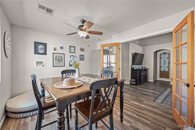 dining area with dark wood-style flooring, a ceiling fan, visible vents, baseboards, and french doors