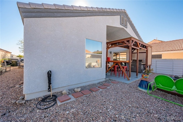 view of side of home featuring fence, a patio, and stucco siding