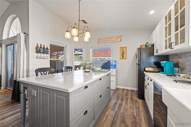 kitchen with white cabinetry, a kitchen breakfast bar, light countertops, a center island, and glass insert cabinets