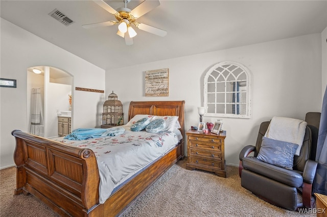 carpeted bedroom with arched walkways, connected bathroom, visible vents, and a ceiling fan