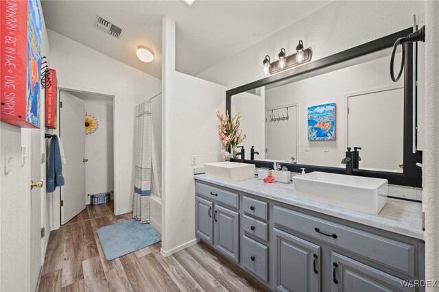 full bathroom featuring wood finished floors, shower / bath combo, a sink, and visible vents