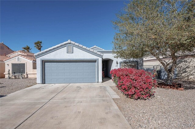 ranch-style home featuring a garage, concrete driveway, a tile roof, and stucco siding