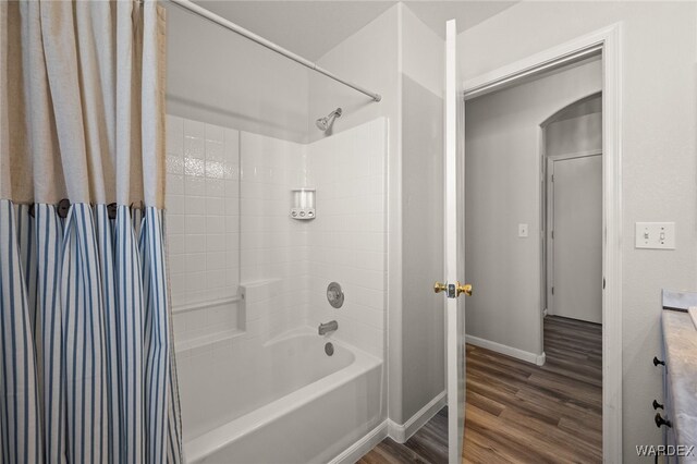 full bath featuring baseboards, shower / tub combo with curtain, and wood finished floors