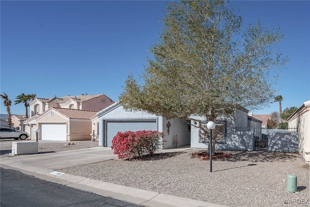 view of front of home featuring stucco siding, concrete driveway, fence, a garage, and a residential view