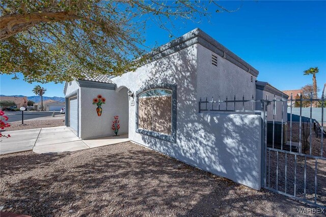 view of home's exterior featuring a garage, fence, concrete driveway, and stucco siding