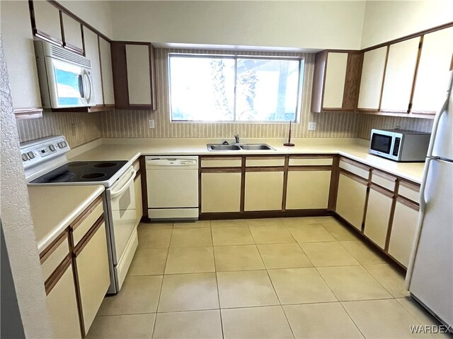 kitchen with light tile patterned floors, light countertops, backsplash, a sink, and white appliances