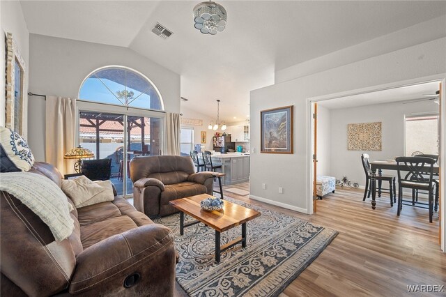 living area with light wood-style floors, a wealth of natural light, visible vents, and lofted ceiling