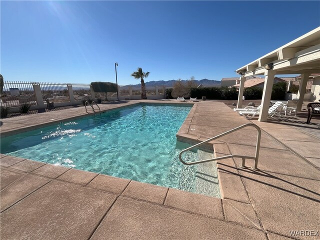 pool with fence, a mountain view, and a patio