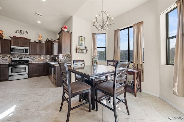 dining space with light tile patterned floors, baseboards, visible vents, lofted ceiling, and a chandelier