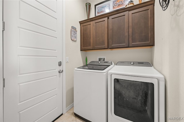 washroom featuring light tile patterned floors, separate washer and dryer, and cabinet space