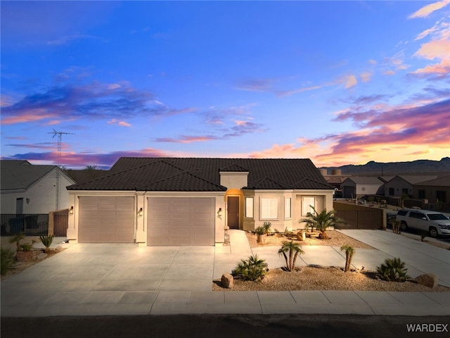 ranch-style home with a garage, a tiled roof, fence, and driveway