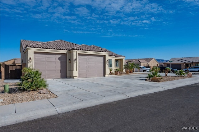 ranch-style house featuring driveway, a tile roof, a residential view, an attached garage, and stucco siding