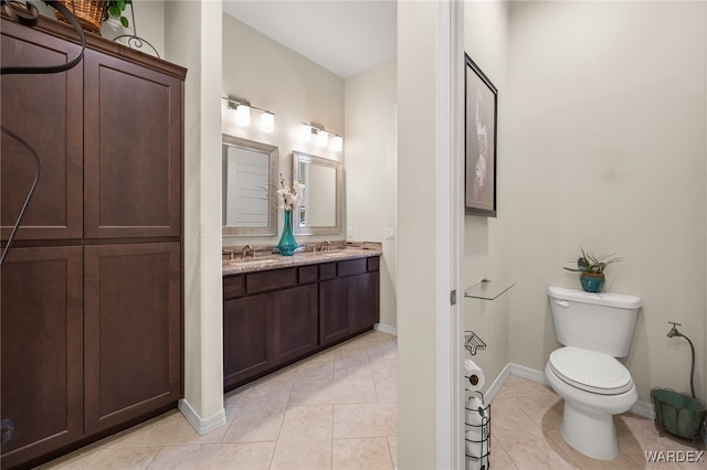 full bathroom featuring double vanity, toilet, a sink, tile patterned flooring, and baseboards