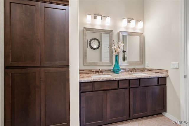 full bath with double vanity, a closet, a sink, and baseboards