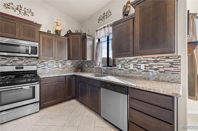 kitchen with stainless steel appliances, tasteful backsplash, a sink, and light stone countertops