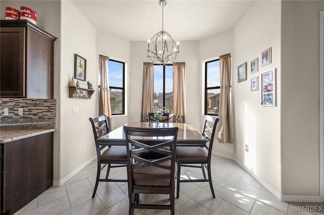 dining space with light tile patterned flooring, baseboards, and an inviting chandelier