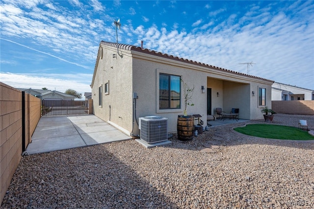 rear view of property featuring a patio, a fenced backyard, central AC, a tile roof, and stucco siding