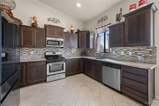 kitchen featuring stainless steel appliances, backsplash, stone countertops, and a sink