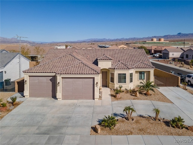 mediterranean / spanish house featuring fence, a tile roof, a residential view, and stucco siding