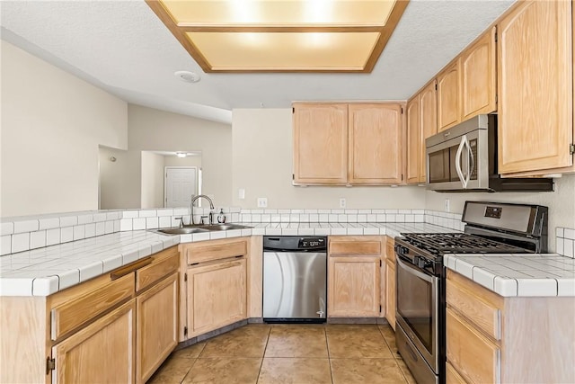1951 E Oatman Pl, Mohave Valley, AZ 86440 - kitchen featuring stainless steel appliances, light brown cabinets, a peninsula, lofted ceiling, and light tile patterned floors
