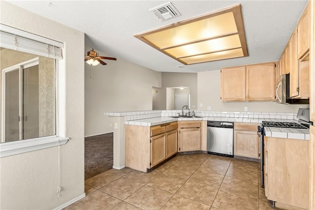 1951 E Oatman Pl, Mohave Valley, AZ 86440 - kitchen with stainless steel appliances, light brown cabinetry, tile countertops, a ceiling fan, and a peninsula