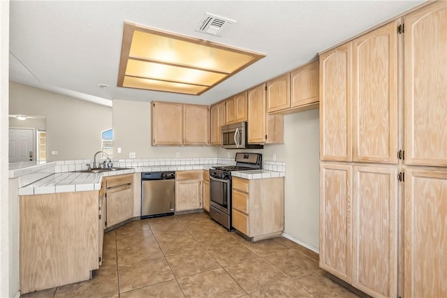 1951 E Oatman Pl, Mohave Valley, AZ 86440 - kitchen featuring light brown cabinets, stainless steel appliances, tile counters, light tile patterned flooring, and a peninsula