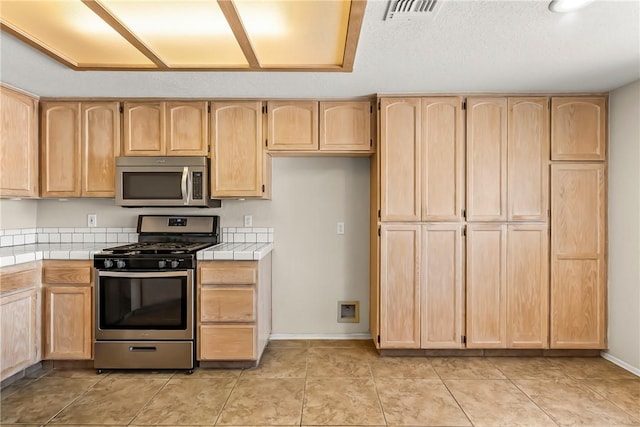 1951 E Oatman Pl, Mohave Valley, AZ 86440 - kitchen with appliances with stainless steel finishes, tile countertops, and light brown cabinetry