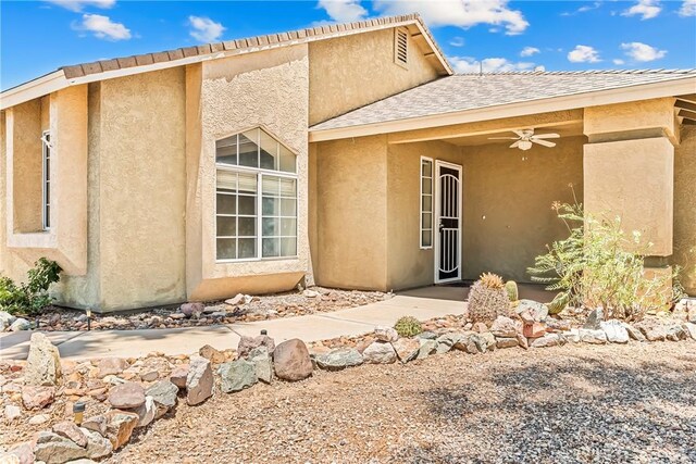 1951 E Oatman Pl, Mohave Valley, AZ 86440 - view of exterior entry featuring stucco siding, a ceiling fan, and roof with shingles