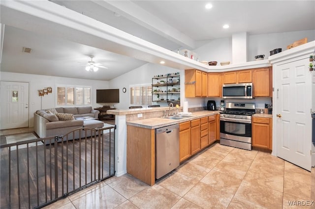 kitchen with ceiling fan, appliances with stainless steel finishes, a sink, a peninsula, and lofted ceiling