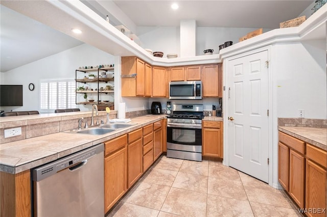 kitchen featuring appliances with stainless steel finishes, a sink, light countertops, a peninsula, and lofted ceiling