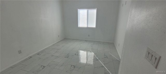 empty room featuring marble finish floor and baseboards