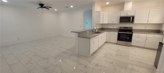 kitchen featuring white cabinets, appliances with stainless steel finishes, a peninsula, marble finish floor, and a sink