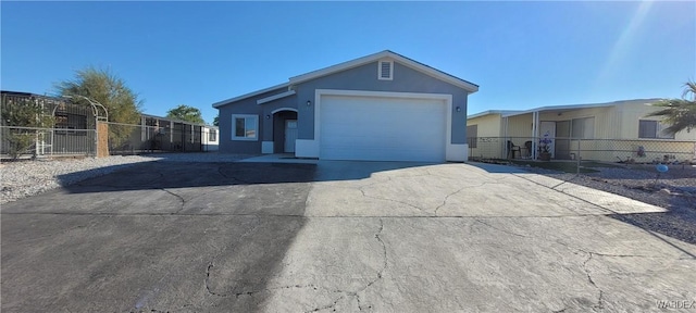 view of front of home with a garage, driveway, fence, and stucco siding