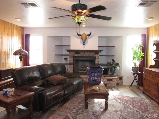 living room with a wealth of natural light, wood walls, and visible vents