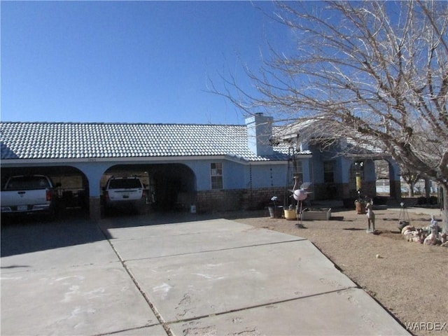 view of property exterior with driveway, a chimney, a tile roof, and stucco siding