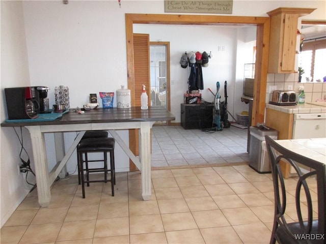 kitchen featuring dishwasher, tasteful backsplash, light tile patterned floors, and tile counters