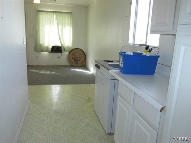 kitchen with light floors, light countertops, white cabinetry, and baseboards