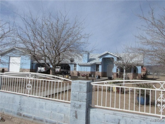 view of front facade featuring a garage, brick siding, driveway, and fence