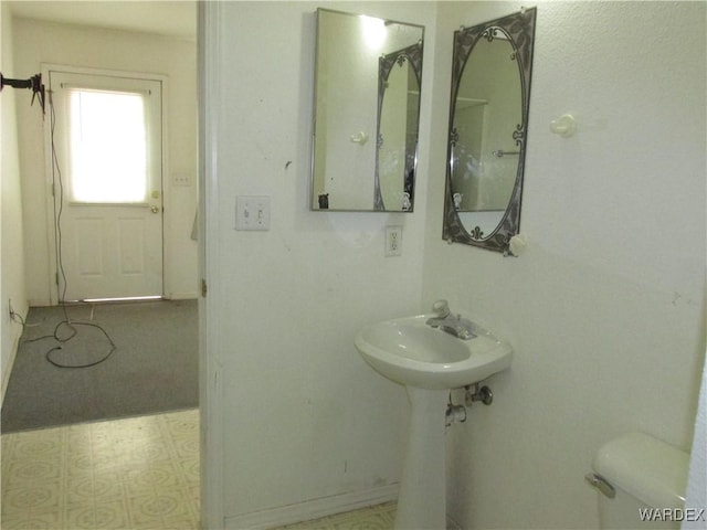 half bathroom with toilet, a sink, and tile patterned floors