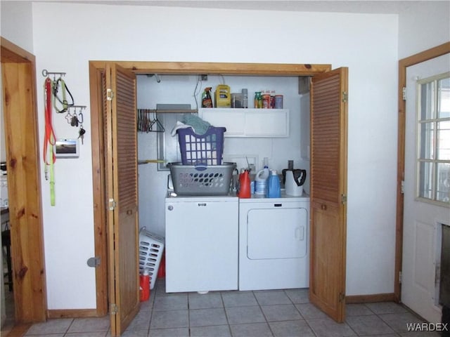 washroom with baseboards, washer and dryer, and light tile patterned flooring